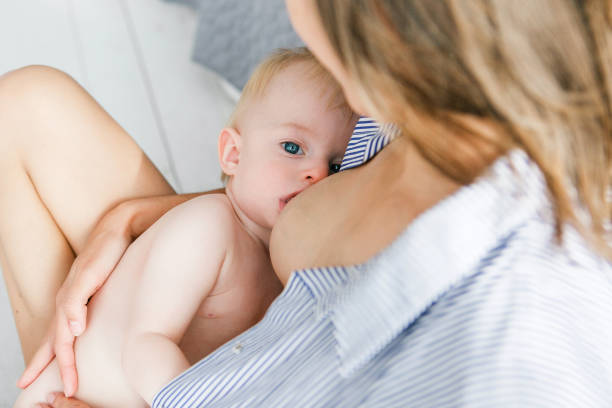 Mother breast feeding newborn baby. Child looking to camera Mother breast feeding newborn baby. Child looking to camera. nipple stock pictures, royalty-free photos & images