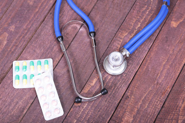 istock Medical stethoscope and tablets isolated on wooden background 884155556
