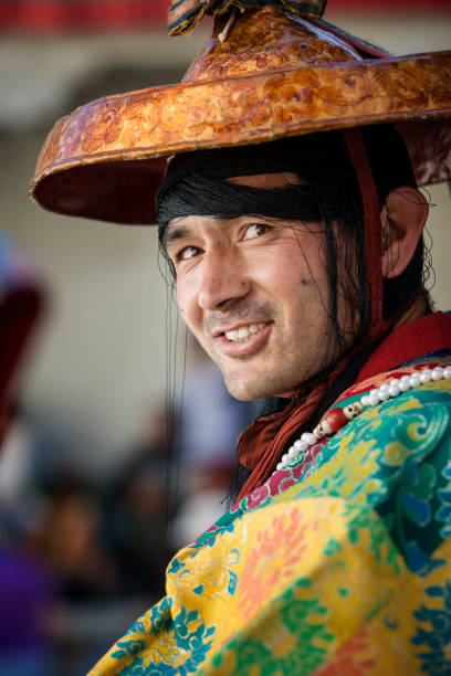Buddhist monk in traditonal costume during monastery festival Phyang, India - July 14, 2015: Buddhist monk in traditonal costume during monastery festival while he is watching and listening to traditional music during in a festival in the courtyard of Phyang Monastery, Ladakh. phyang monastery stock pictures, royalty-free photos & images