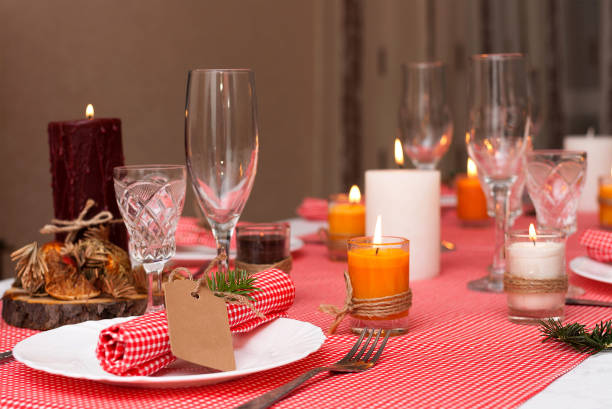 istock Festive composition with candles and plates. Table decoration. A beautiful table setting, red table cloth, tablecloth in the box. Christmas dinner. A Napkin decorated with inscription Merry Christmas. 884178990