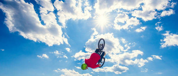 bmx всадника делать сальто против солнечного облачного неба - bmx cycling bicycle cycling backflipping стоковые фото и изображения