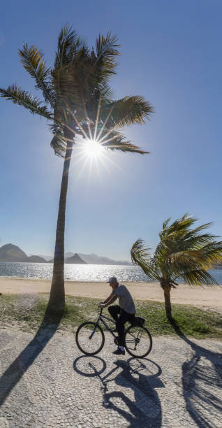 brasilianischen mann auf dem fahrrad in icarai strandnähe in niterói rio de janeiro - brazil bicycle rio de janeiro outdoors stock-fotos und bilder