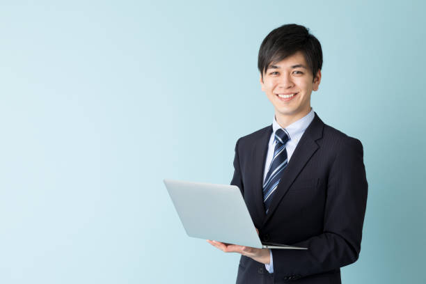 青の背景に分離したアジア系のビジネスマンの肖像画 - ノートパソコン 写真 ストックフォトと画像