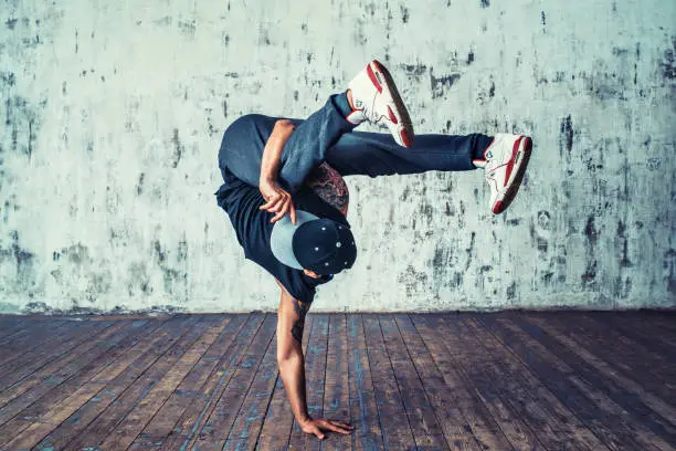 Young man break dancing on wall background