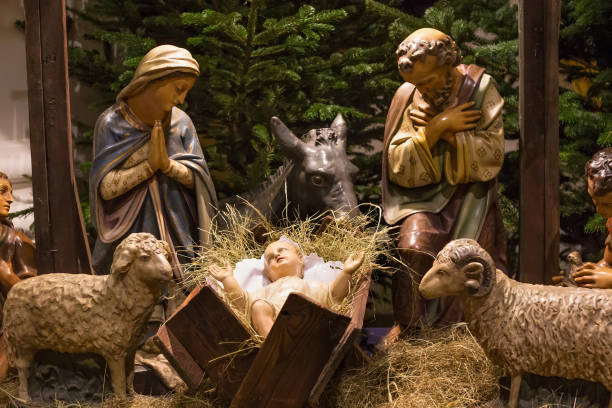 A traditional Nativity scene depicting the birth of Jesus, featuring figurines of Mary, Joseph, baby Jesus in a manger, shepherds, wise men, an angel, and animals, illuminated by festive lights