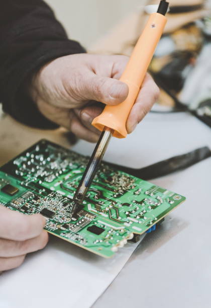 istock Man Repairing Electronic Circuitr using welder tool 884243754