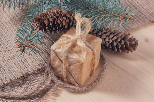 istock Gift in retro styles and christmas tree with cones on a wooden surface 884246138