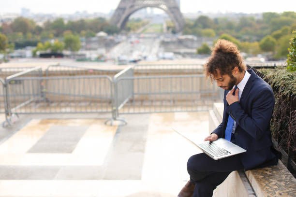 istock Mixed blood businessman working with laptop near Eiffel Tower in 884260722