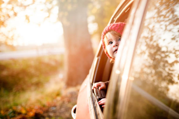 the little boy is looking from the car window