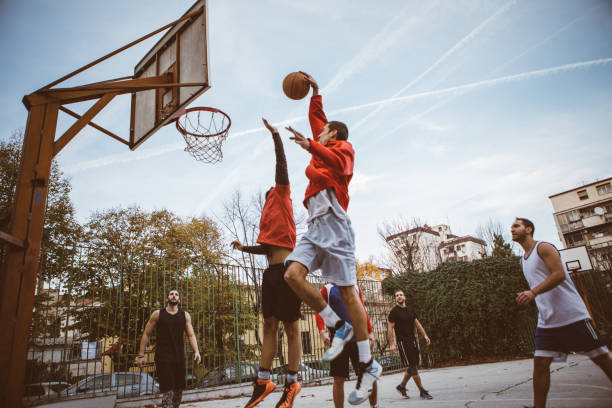 Leisure activities Group of male friends playing basketball at city court courtyard photos stock pictures, royalty-free photos & images