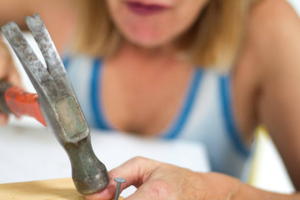 istock Pain and Injury: Woman Hitting Thumb with Hammer 884284812