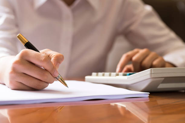 istock The merchant USES a calculator, paper and pencil for financial analysis. Financial chart data 884300778