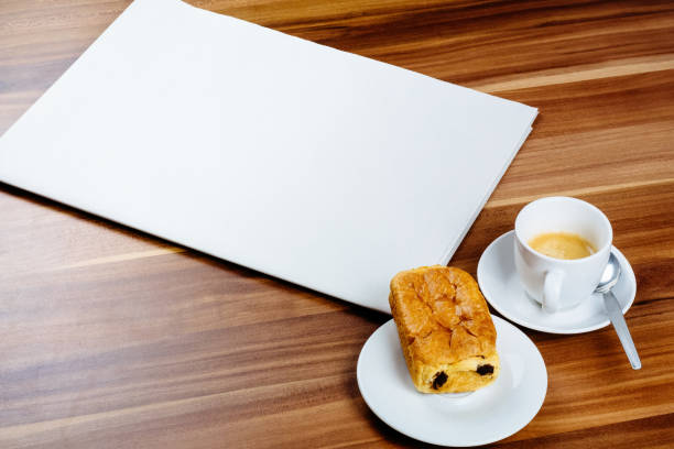 istock Empty newspaper, espresso and chocolate croissant on a wooden table 884321136