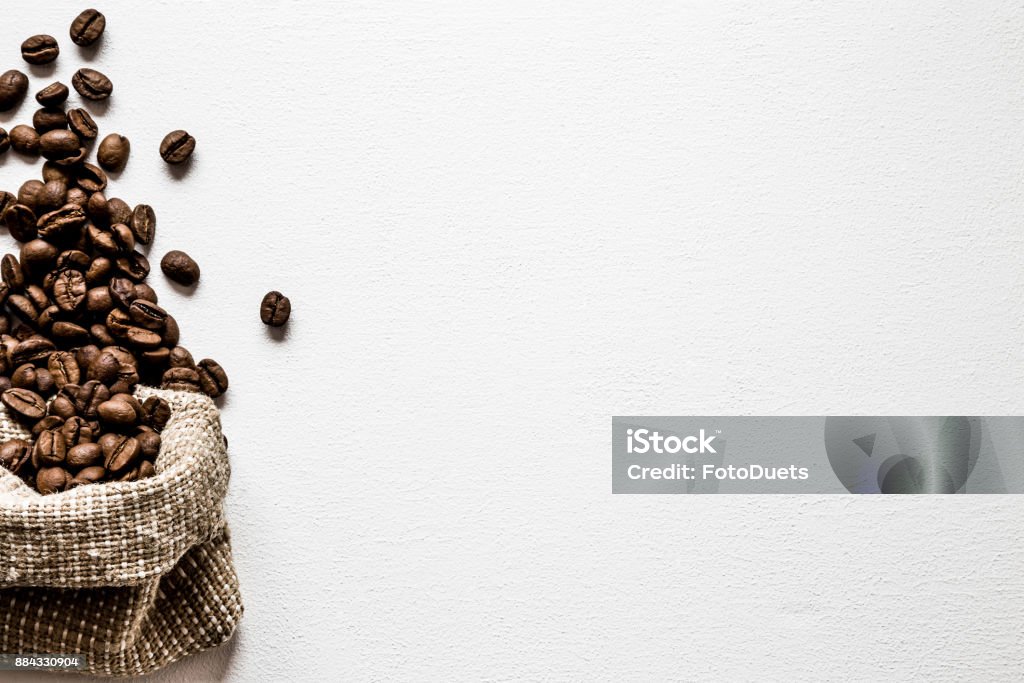 Brown beans with burlap bag on the white table. Harvest of coffee in different countries. Choice of the best sort and quality coffee. Empty place for a text. Web background. Mug Stock Photo