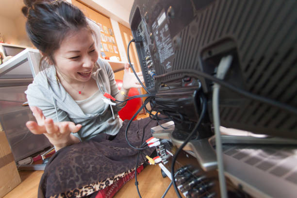 istock Young woman connecting cables to TV 884350020