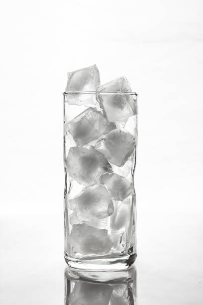 istock Glass with ice cubes on white background 884355632