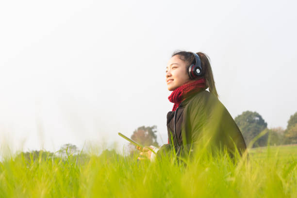 istock young woman sitting on lawn using tablet 884358408