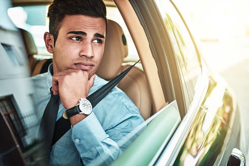 Shot of a young businessman looking worried while driving a car