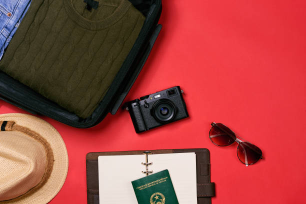 istock Preparation for travel concept - passport, camera, hat, chrismas decorations on red background 884359482