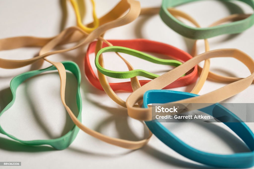 Normal And Colored Rubber Bands Colored and normal rubber bands laying on a white background close up Rubber Band Stock Photo