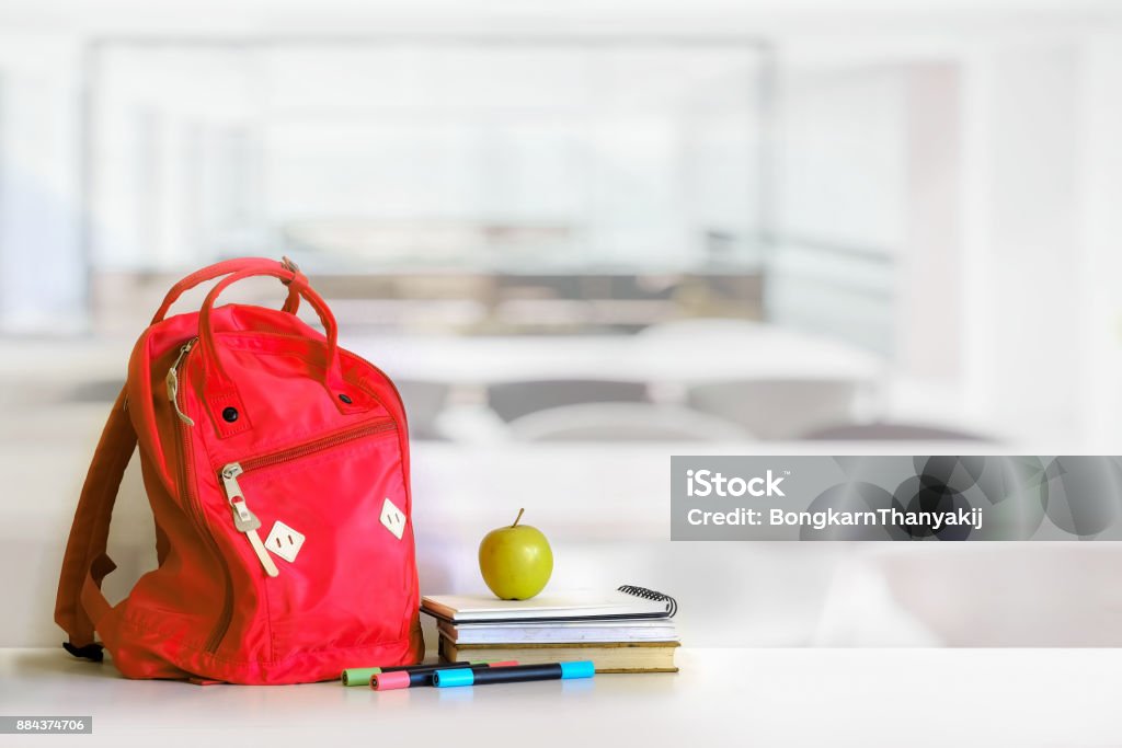 Red backpack and books school supplies in classroom. Backpack Stock Photo
