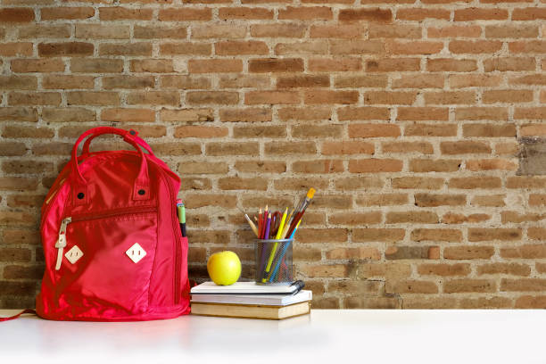 istock Red backpack and books school supplies on desk. 884374788