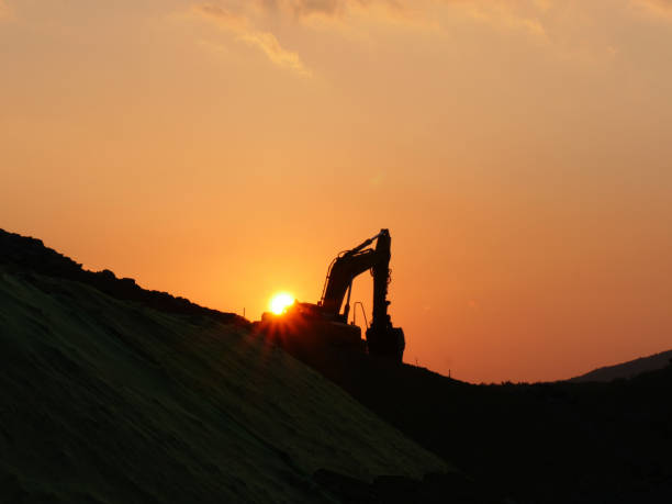 istock Working mechanical excavator silhouette in sunset 884375200