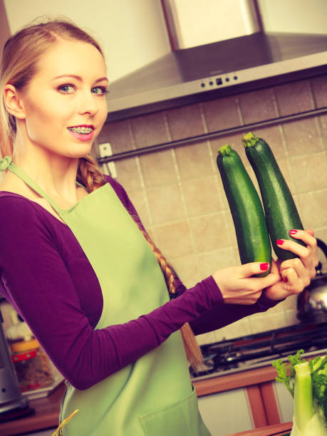 istock Woman in kitchen holds zucchini vegetable 884377808