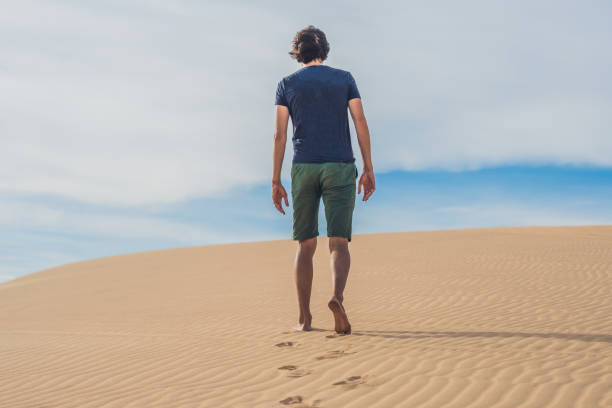istock A man is walking in the desert Vietnam, Mui Ne 884384612