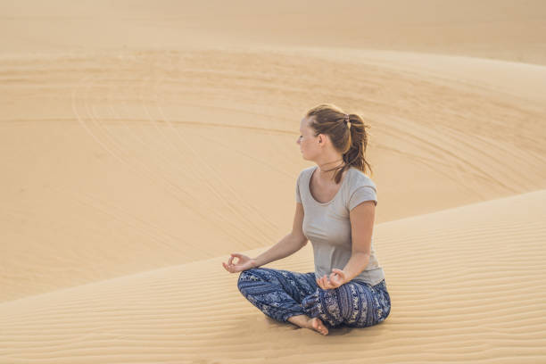 istock Young woman meditating in the desert 884384744