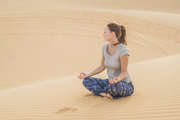 istock Young woman meditating in the desert 884384746