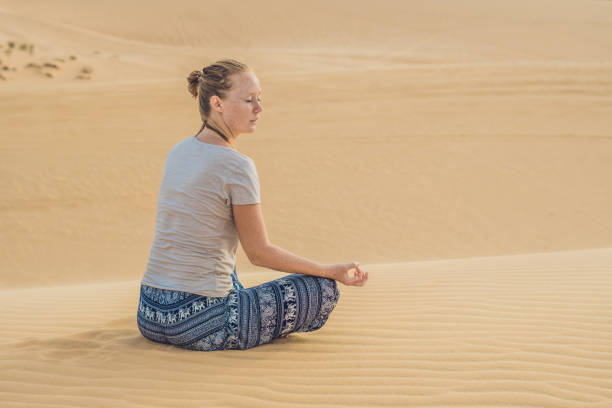 istock Young woman meditating in the desert 884384788