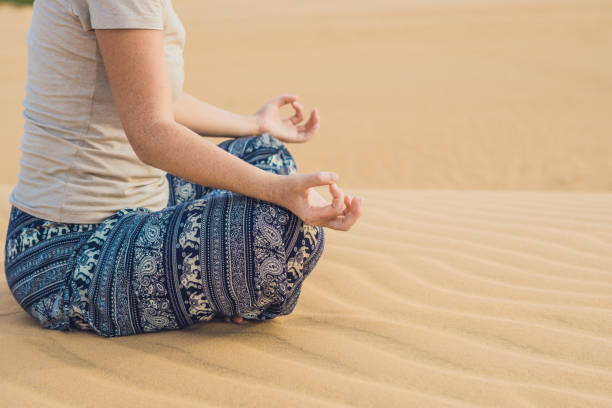 istock Young woman meditating in the desert 884384798