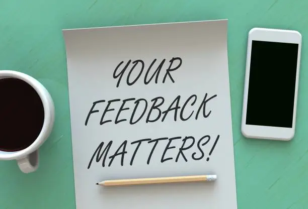 Photo of Your Feedback Matters, message on paper, smart phone and coffee on table