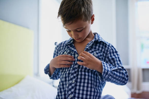 Part of being a kid Cropped shot of a young boy getting dressed in his bedroom in the morning buttoning stock pictures, royalty-free photos & images