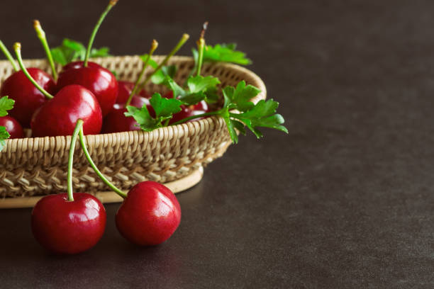 istock Fresh cherries on wood basket put on black granite table in side view with copy space. Cherry have high vitamin and have sweet and sour taste. Fruit background and wallpaper concept. 884387786