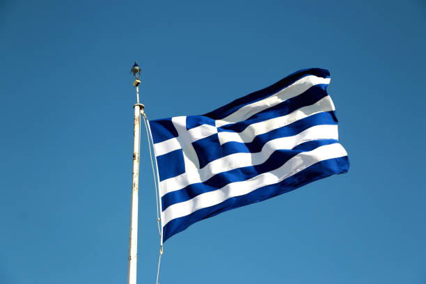 istock national flag of Greece against blue sky background 884430908