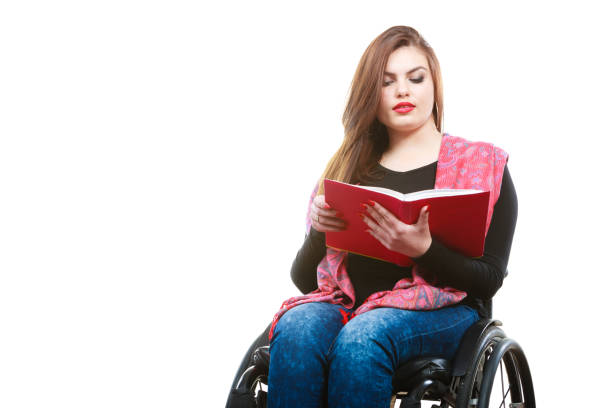 istock Young disabled woman in wheelchair with book. 884440312