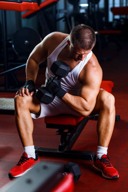 istock Young man exercising with weight in the gym. 884453416