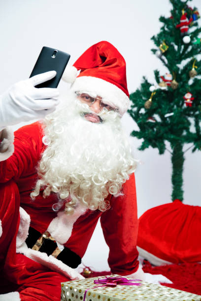 istock Man wearing Santa Claus costume taking selfie 884462664