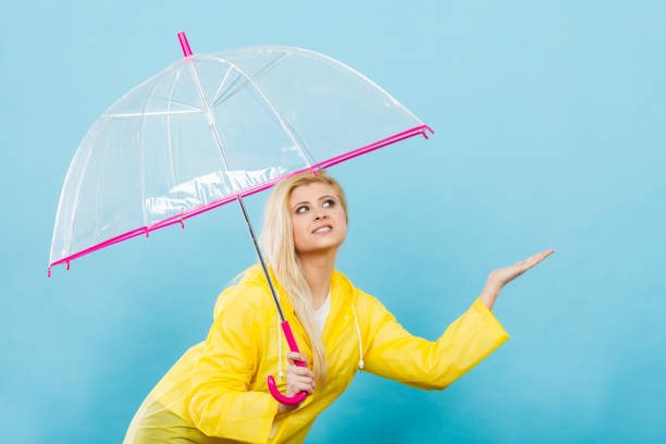 istock Woman wearing raincoat holding umbrella checking weather 884468558