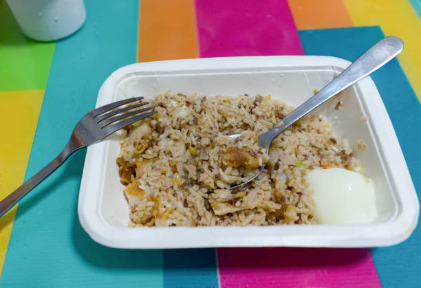 istock galic fried rice and whtie boil egg in paper rectangle bowl and scooped spoon with fork on colorful table 884479246