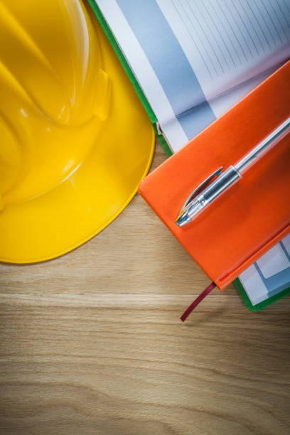 istock Notepads pen building helmet on wooden board construction concep 884480112