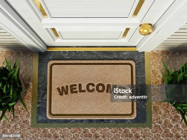 Door Mat With Welcome Word Standing In Front Of The House Door Stock Photo - Download Image Now