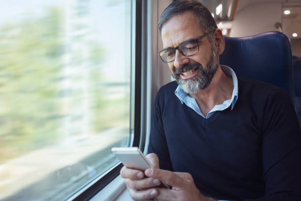 istock Mature man in train travelling using mobile phone 884498156