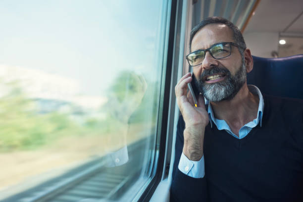 istock Mature man in train travelling using mobile phone 884498202