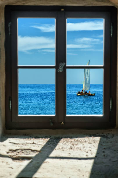 istock into the freedom - sailing ship, catamaran behind old window 884498754