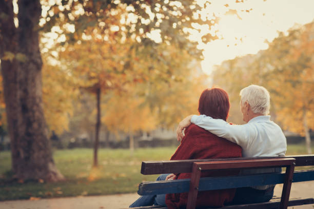 istock Happy autumn-senior couple on park bench 884499112
