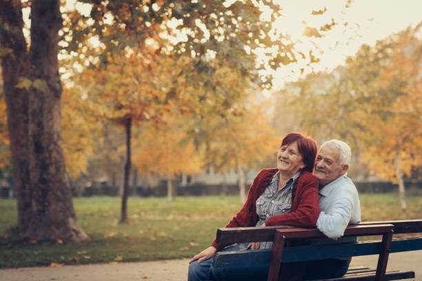 istock Happy autumn-senior couple on park bench 884505448