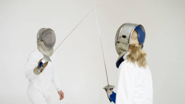 istock Two fencers having training attack and defence exercises in fencing on white background 884505820